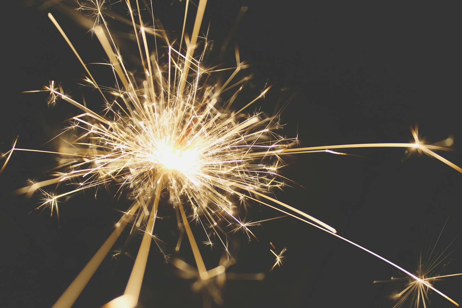 Photo by Malte Luk Close-up of a dazzling sparkler bursting with light against a dark background, perfect for celebrations.