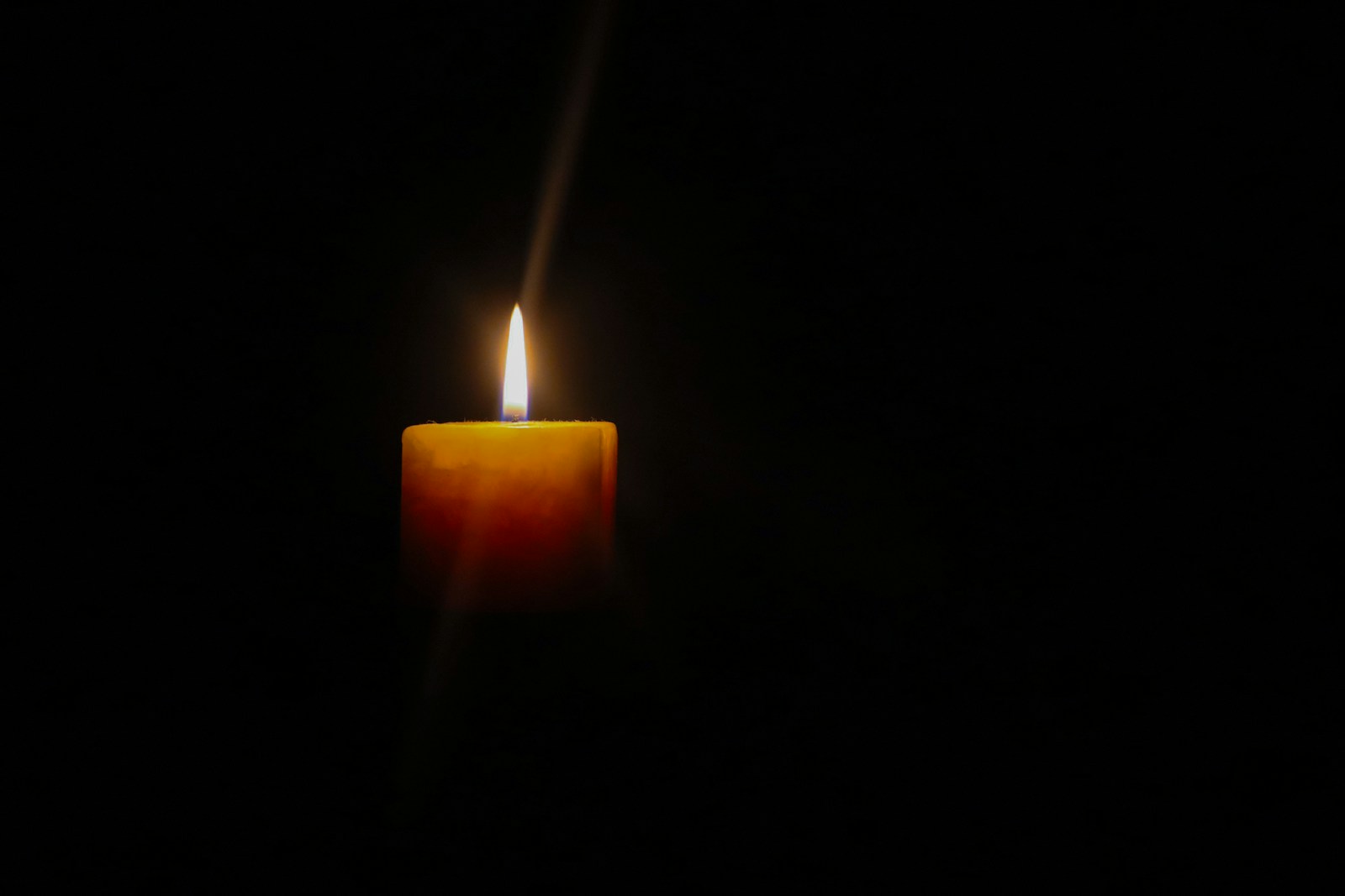a single lit candle glowing against a dark background, symbolising hope and recovery from neurodivergent burnout in women