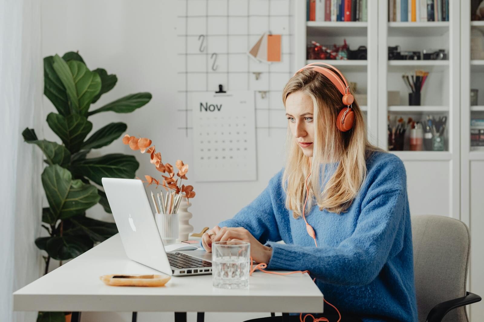 eine Frau, die konzentriert mit Kopfhörern an einem hellen, organisierten Schreibtisch an ihrem Laptop arbeitet, als Symbol dafür, wie neurodivergente Inklusion am Arbeitsplatz aussehen kann, wenn Umgebungen für verschiedene Denkweisen gestaltet werden